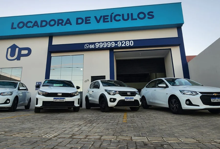 Fachada da UP Locadora de Veículos com quatro carros brancos expostos, incluindo modelos Fiat e Chevrolet.