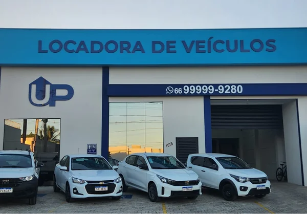 Vista frontal da UP Locadora de Veículos com cinco carros da frota estacionados em frente à loja.