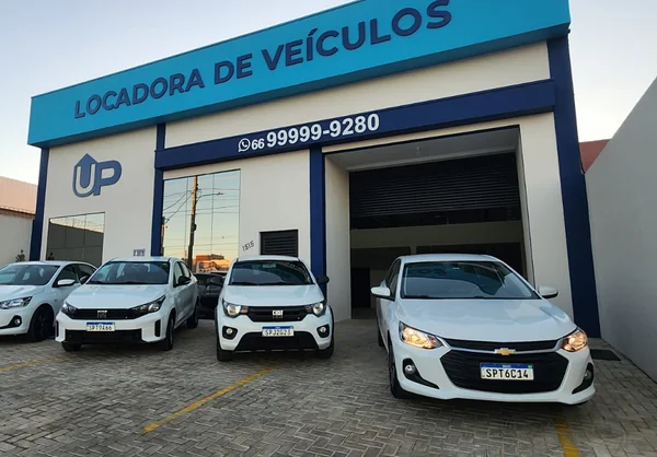 Fachada da UP Locadora de Veículos com carros da frota em exposição na entrada e veículos adicionais na garagem.